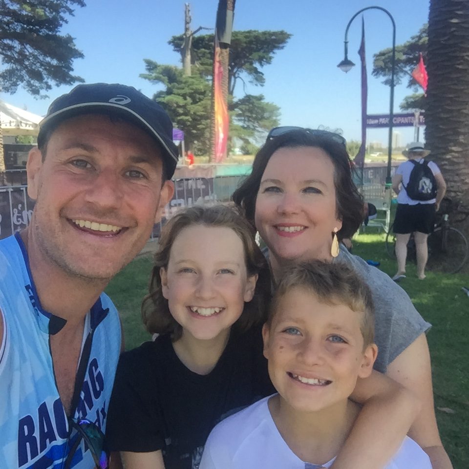 A smiling family raise their glasses in front of an ocean view